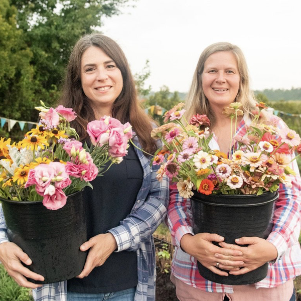 Lisa Crook and her business partner Jenni holding buckets of blooms