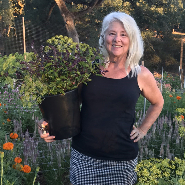 Tammy Lissner standing in her flower field with a bucket of blooms