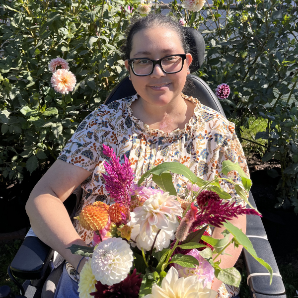 Jesica Rubio in her garden with a handful of colorful blooms